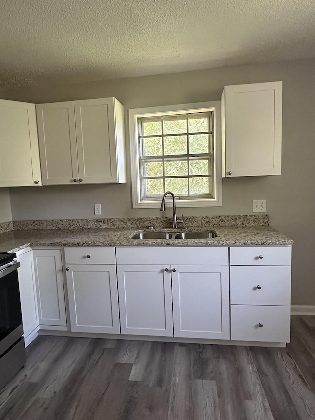 kitchen featuring a textured ceiling, stainless steel stove, white cabinetry, and sink