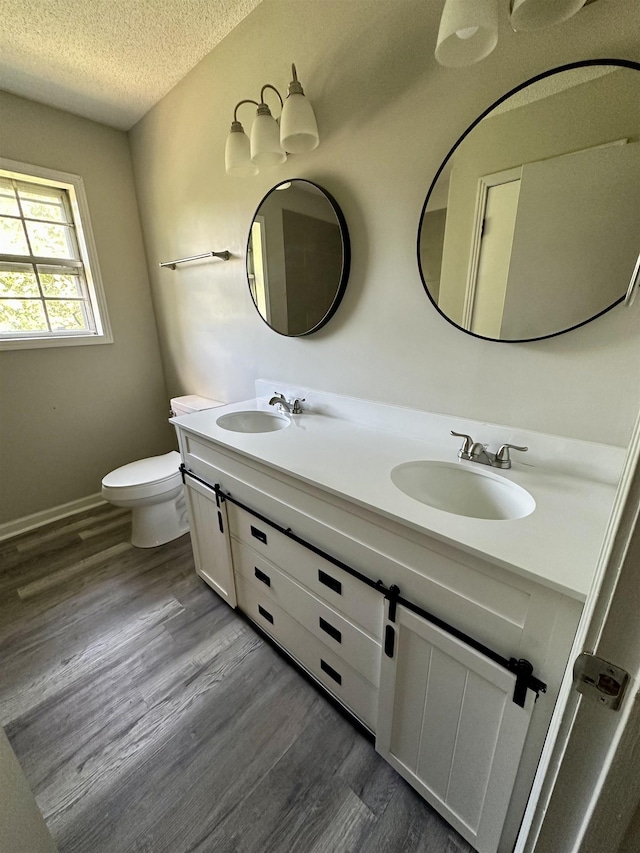 bathroom featuring hardwood / wood-style flooring, vanity, a textured ceiling, and toilet