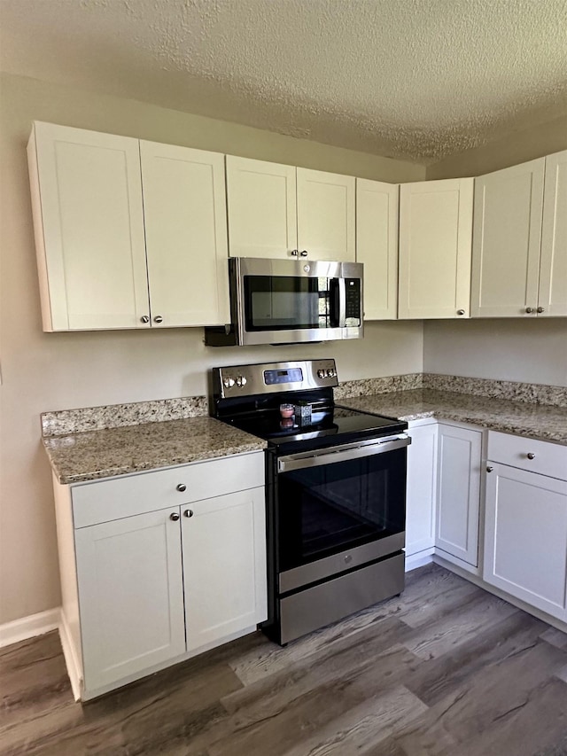 kitchen featuring stone counters, light hardwood / wood-style flooring, a textured ceiling, white cabinetry, and stainless steel appliances