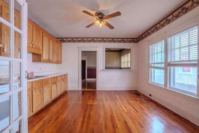 kitchen featuring light wood-type flooring, ceiling fan, a textured ceiling, and sink