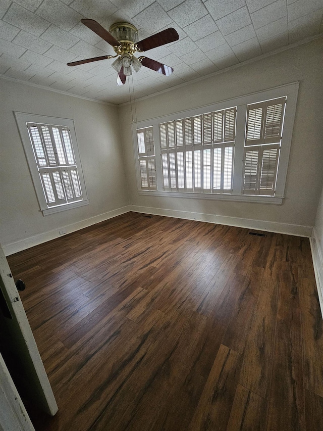 empty room with dark hardwood / wood-style flooring, ceiling fan, and ornamental molding