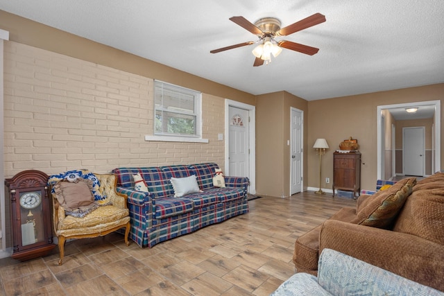 living room with ceiling fan, a textured ceiling, and brick wall