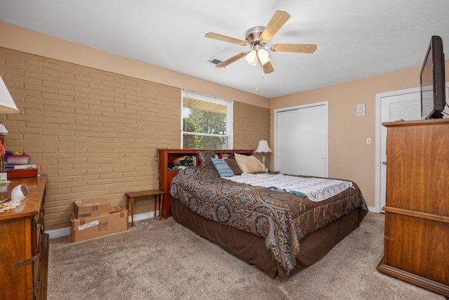 carpeted bedroom with ceiling fan and brick wall