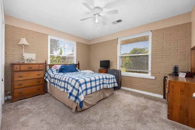 bedroom with ceiling fan, light colored carpet, and brick wall