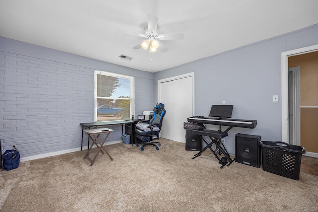 home office with ceiling fan, light carpet, and brick wall