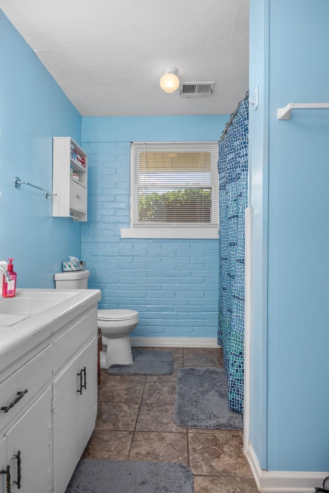 bathroom featuring a shower with shower curtain, vanity, toilet, and brick wall