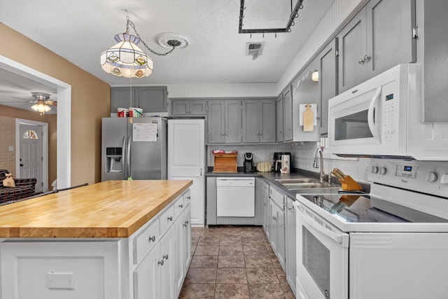 kitchen with ceiling fan, a center island, wood counters, a textured ceiling, and white appliances