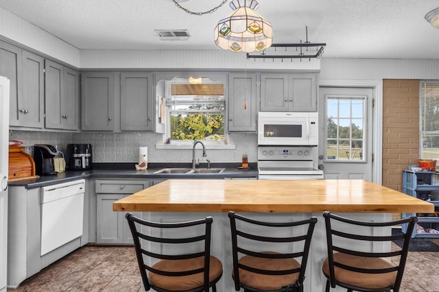 kitchen with gray cabinetry, white appliances, sink, a textured ceiling, and butcher block counters