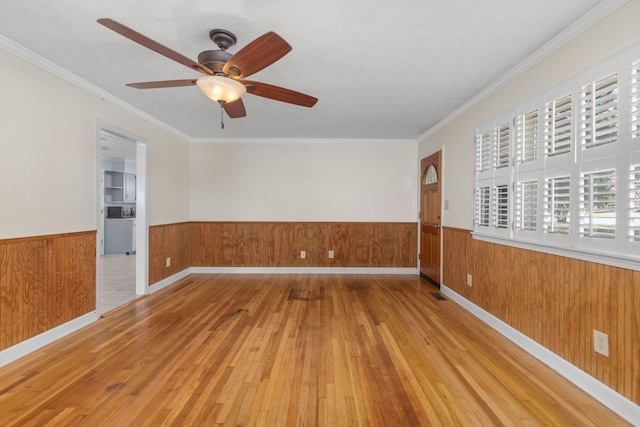 empty room featuring ceiling fan, ornamental molding, and light hardwood / wood-style flooring