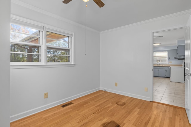 empty room with light hardwood / wood-style floors, ceiling fan, crown molding, and sink