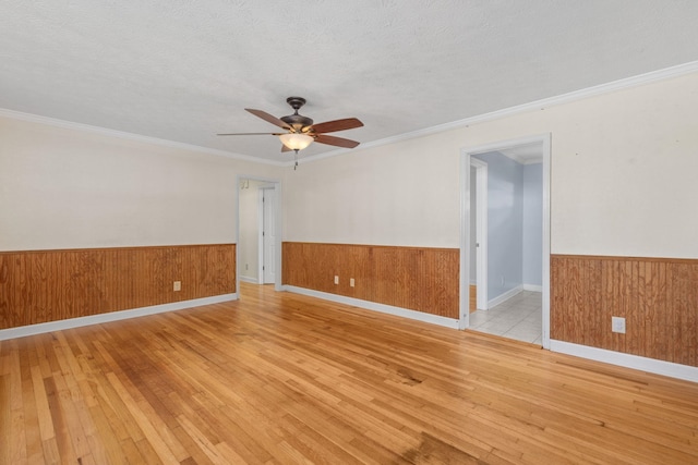 empty room featuring crown molding, ceiling fan, a textured ceiling, and light wood-type flooring