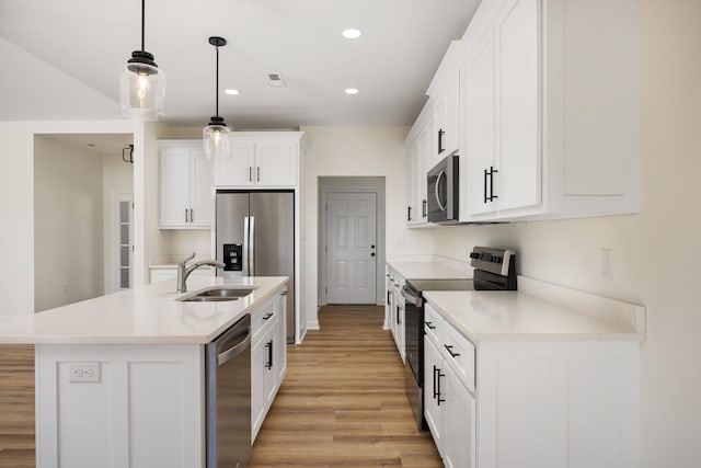 kitchen featuring sink, hanging light fixtures, a kitchen island with sink, appliances with stainless steel finishes, and white cabinets