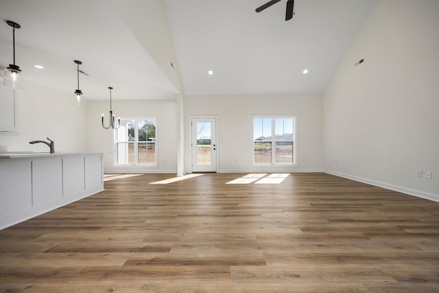 unfurnished living room featuring high vaulted ceiling, sink, hardwood / wood-style floors, and ceiling fan