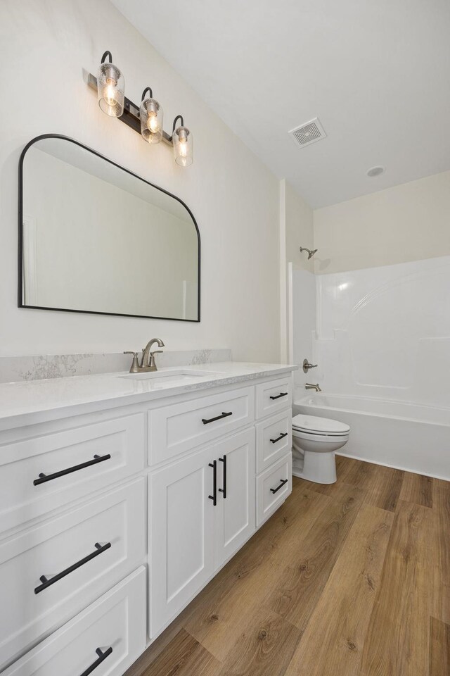 full bathroom featuring toilet, wood-type flooring, vanity, and shower / bathing tub combination