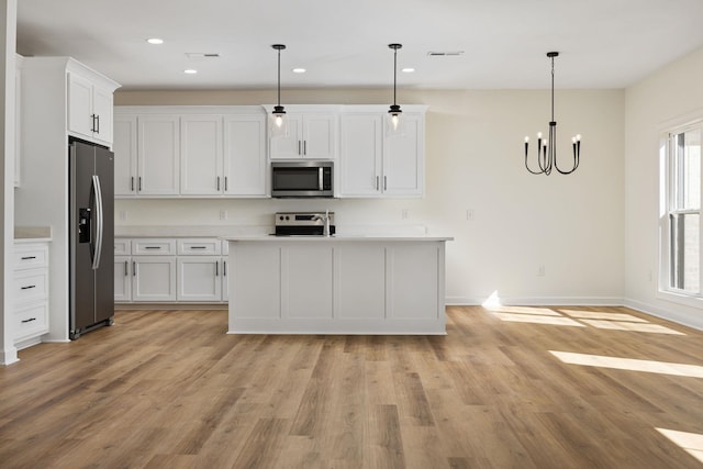 kitchen with decorative light fixtures, white cabinets, stainless steel appliances, and a notable chandelier