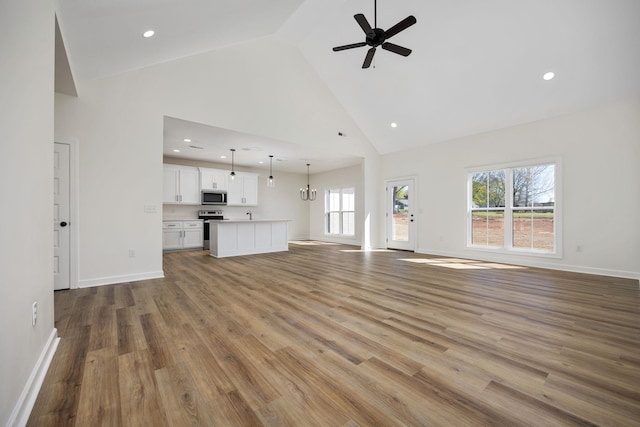 unfurnished living room with high vaulted ceiling, ceiling fan, and hardwood / wood-style flooring