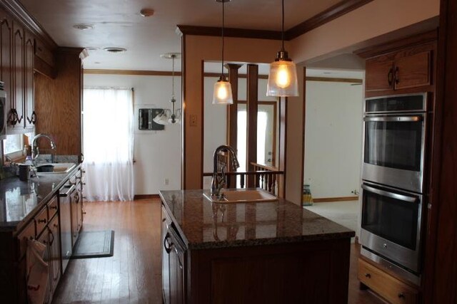 kitchen featuring pendant lighting, a center island, dark stone counters, sink, and stainless steel double oven