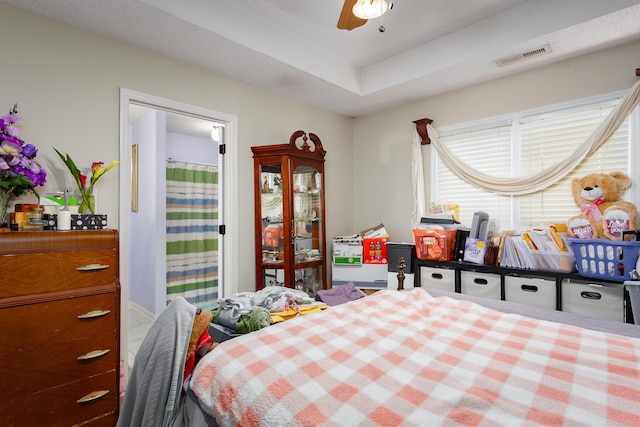 bedroom with ceiling fan and a tray ceiling