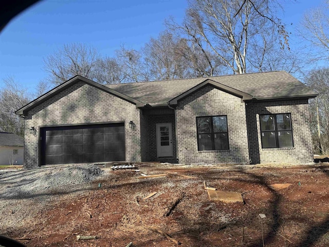 single story home featuring a garage, driveway, roof with shingles, and brick siding