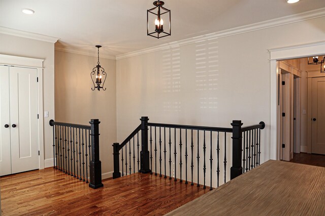 hall featuring wood-type flooring, an inviting chandelier, and crown molding