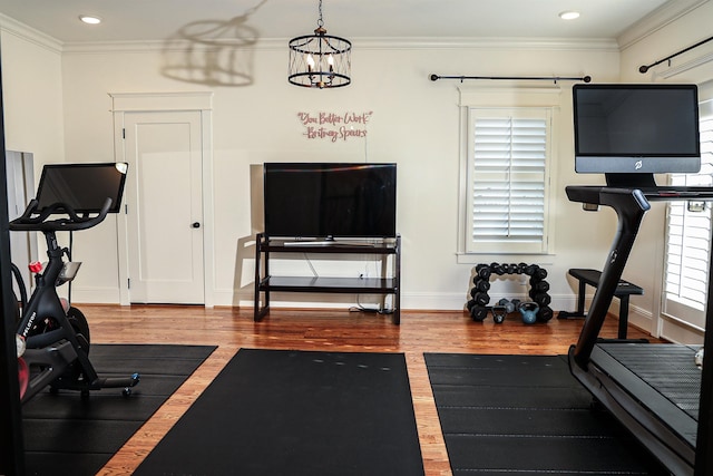 exercise area featuring ornamental molding, a chandelier, and hardwood / wood-style flooring