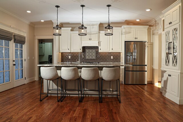 kitchen featuring stone countertops, pendant lighting, stainless steel refrigerator with ice dispenser, and ornamental molding