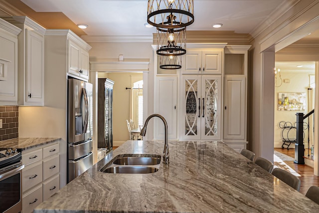 kitchen with a kitchen breakfast bar, sink, stainless steel refrigerator with ice dispenser, and stone counters