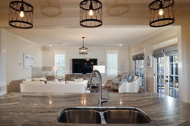 kitchen featuring crown molding, sink, hanging light fixtures, and dark stone counters