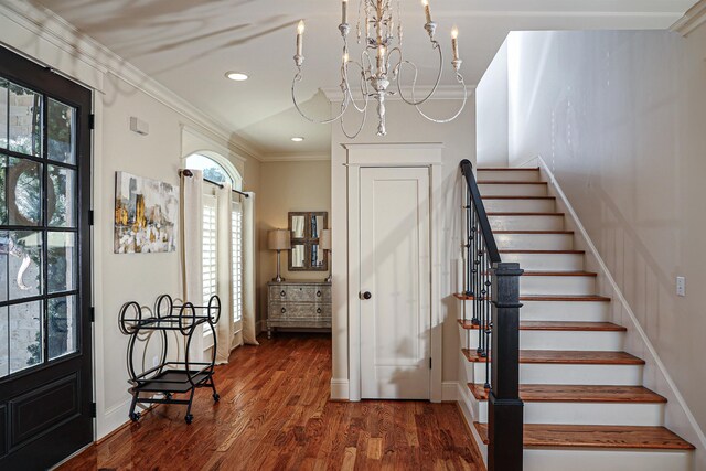 foyer with crown molding, dark hardwood / wood-style floors, and an inviting chandelier