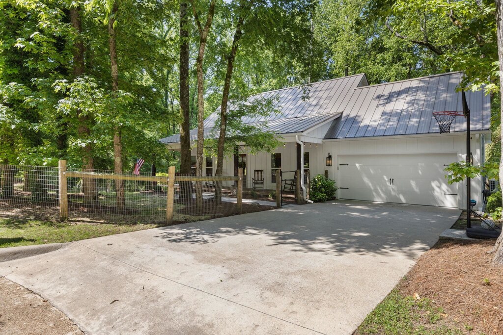 view of front of house featuring concrete driveway, fence, an attached garage, a standing seam roof, and metal roof