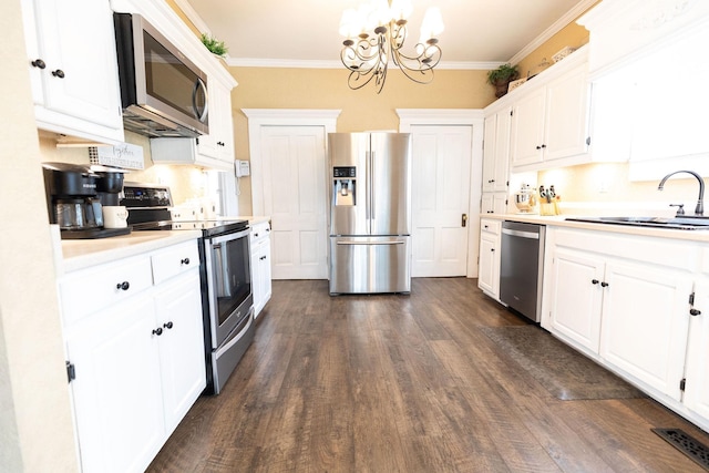 kitchen with decorative light fixtures, white cabinetry, stainless steel appliances, and ornamental molding