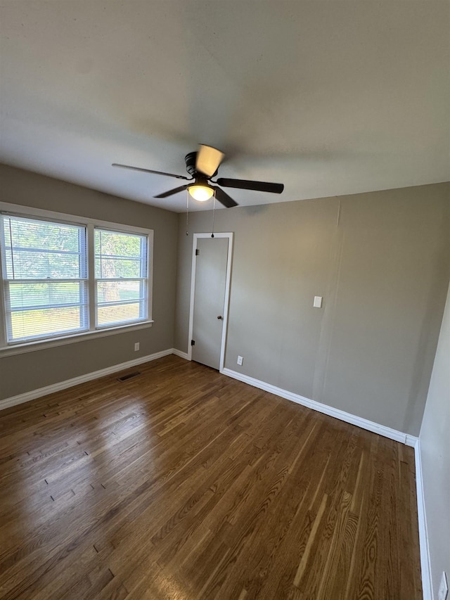  - spare room featuring dark wood-style flooring, a ceiling fan, and baseboards