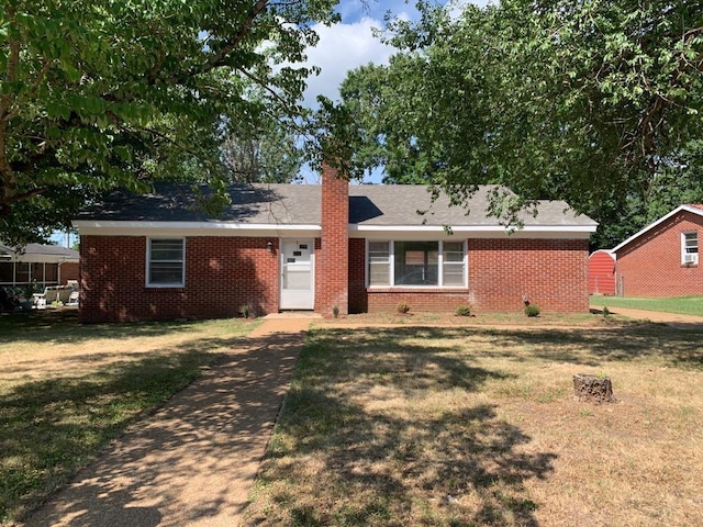 ranch-style home with brick siding, a front lawn, and a chimney