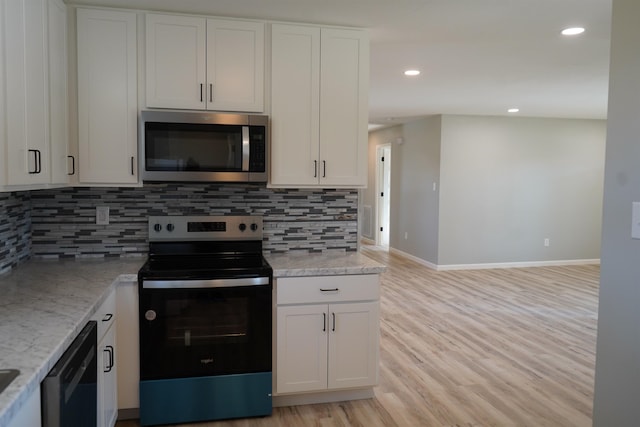 kitchen featuring appliances with stainless steel finishes, light wood-type flooring, tasteful backsplash, light stone counters, and white cabinets