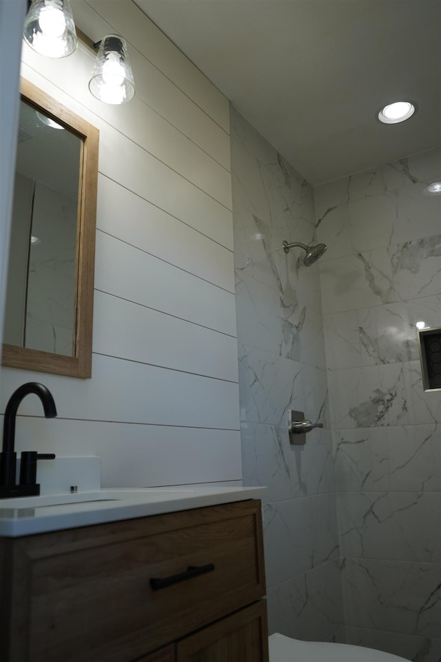 bathroom featuring a tile shower, vanity, and toilet