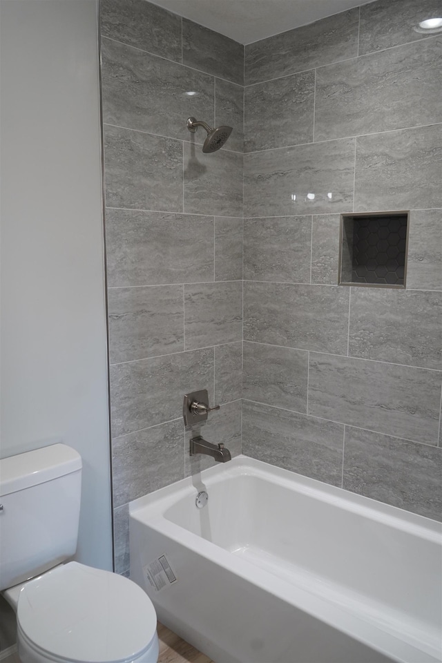 bathroom with toilet and tiled shower / bath