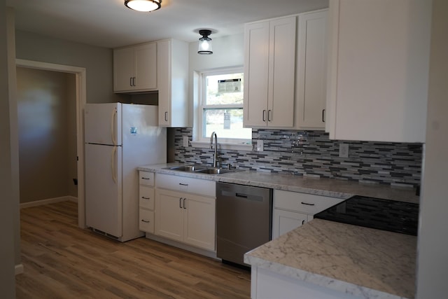 kitchen with white refrigerator, white cabinetry, stainless steel dishwasher, and sink