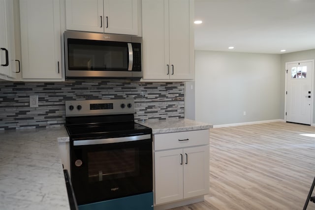 kitchen with light stone countertops, appliances with stainless steel finishes, tasteful backsplash, light hardwood / wood-style flooring, and white cabinets