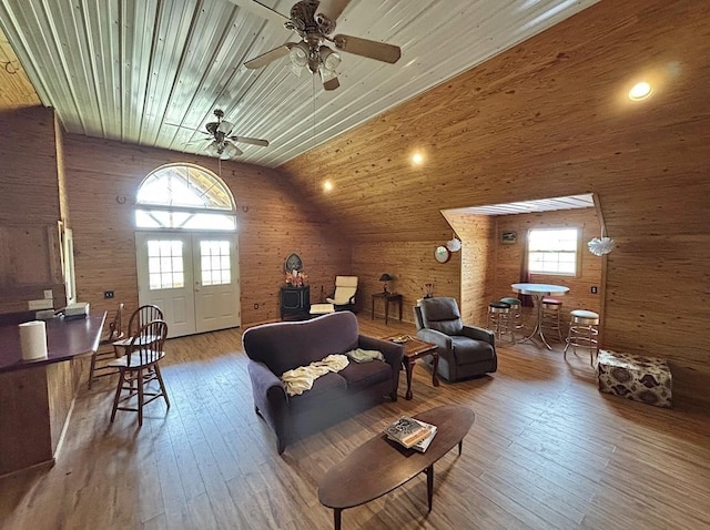  - living area featuring wood ceiling, wood-type flooring, a ceiling fan, high vaulted ceiling, and wooden walls