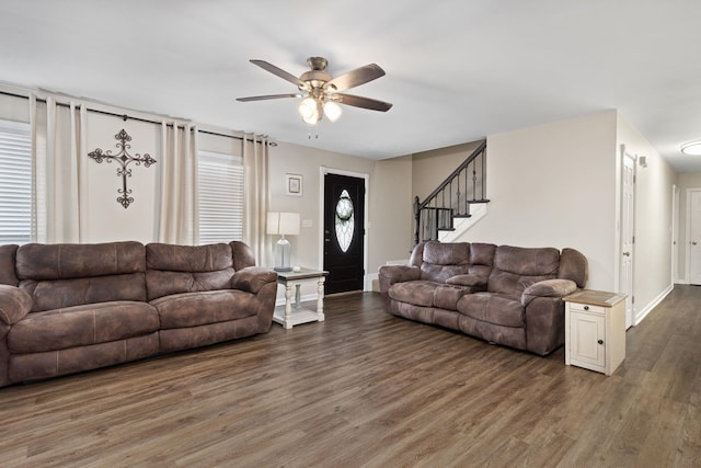 living area featuring stairs, a ceiling fan, baseboards, and wood finished floors