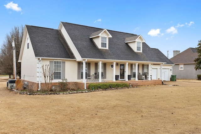 cape cod-style house with stucco siding, a porch, a shingled roof, an attached garage, and central AC unit