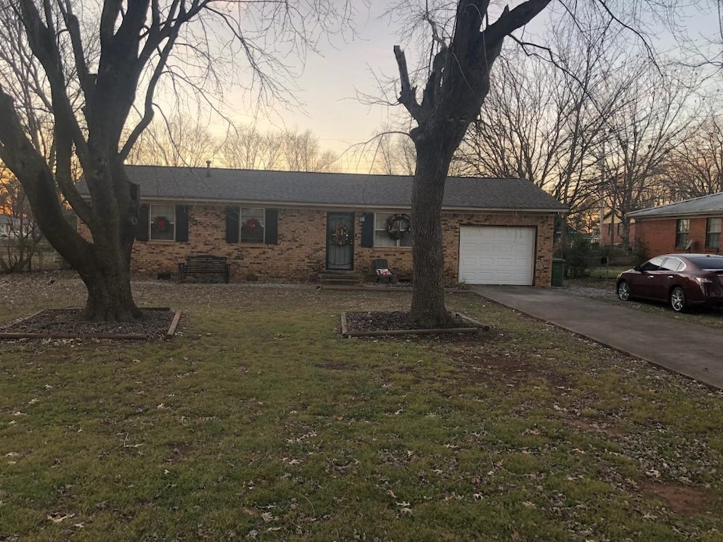 ranch-style home with a garage and a lawn