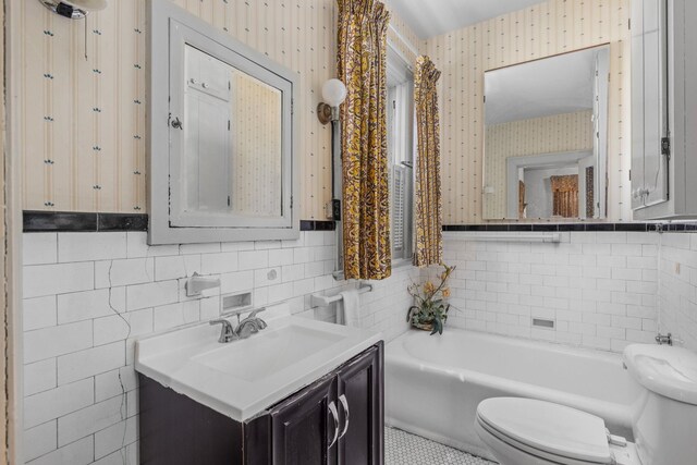 bathroom featuring vanity, a bath, tile walls, and toilet