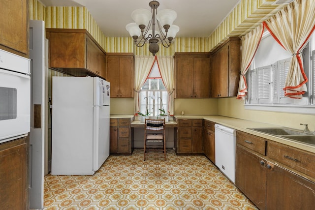 kitchen featuring white appliances, an inviting chandelier, hanging light fixtures, and sink