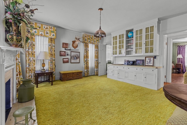 interior space with light carpet, a wealth of natural light, and a tiled fireplace