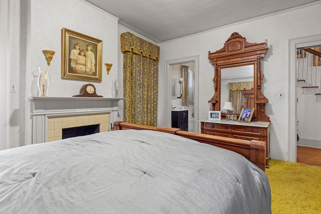 bedroom featuring carpet flooring, a tiled fireplace, and ensuite bath