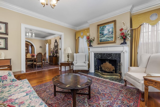 living room featuring a premium fireplace, a chandelier, dark hardwood / wood-style floors, and ornamental molding