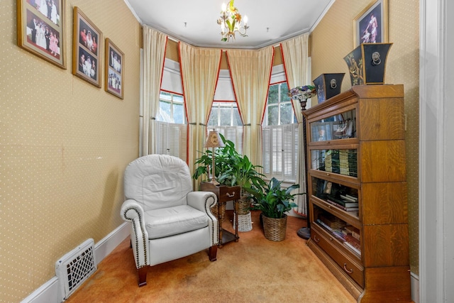 sitting room with carpet floors, crown molding, and an inviting chandelier