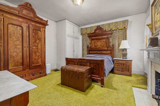 bedroom featuring a tiled fireplace and light colored carpet