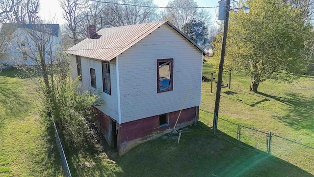  - view of home's exterior featuring a chimney, metal roof, fence, and a lawn